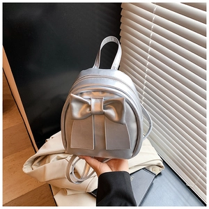 Detail of silver mini backpack with large bow decoration and glossy metallic finish