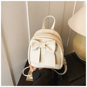 Detailed macro view of the creamy white mini backpack featuring a large decorative bow