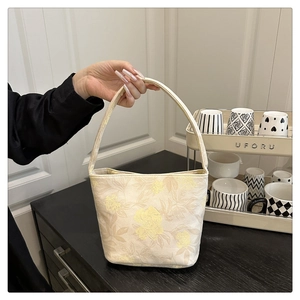 Close-up of elegant floral embroidery on beige canvas tote bag with top handle grip