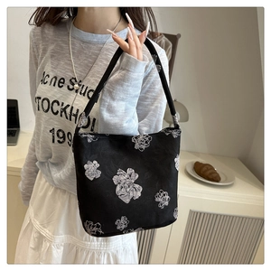 Detail shot of black floral tote bag featuring white flower patterns and durable strap