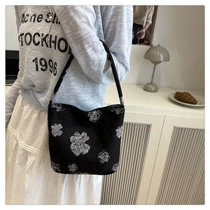 Detail of elegant black jacquard tote bag featuring large white floral embroidery texture
