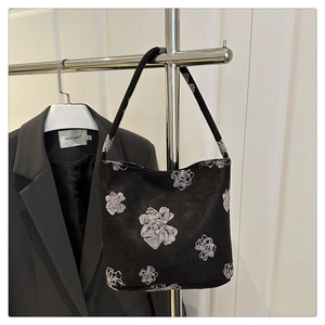 Detail of black fabric tote with white floral patterns on a metal display rack