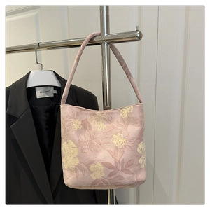 Detail of pink floral canvas handbag hanging on metal rack with a chic suit background