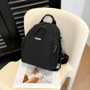 Modern black nylon backpack for women with silver brand plate on stylish white chair