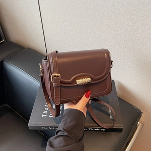 Retro dark brown crossbody bag with gold lock and wavy stitching on leather flap