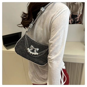 Detail of dark grey underarm bag with bow, chain elements and pearl decorations