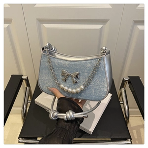Detail of light blue glitter denim handbag with silver bow and pearl chain decoration