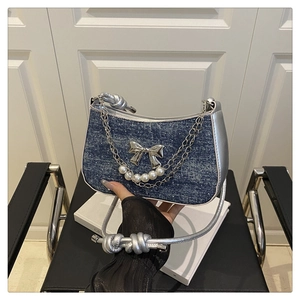 Detail of denim underarm bag with silver metallic bow, pearls and knotted shoulder strap