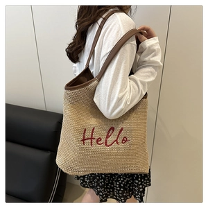 Detail of hand-woven straw tote bag with red Hello embroidery and leather shoulder straps