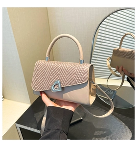 Detail of beige crossbody bag with herringbone weave flap and silver heart lock