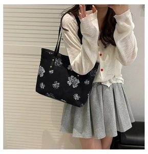 Détail d'un grand sac cabas noir à motifs floraux blancs avec rivets métalliques dorés
