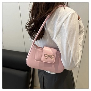 Vue détaillée du sac baguette rose avec nœud doré porté à l'épaule par un mannequin