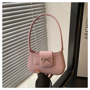 Vue détaillée du sac baguette en cuir rose avec un nœud métallique doré sur le rabat