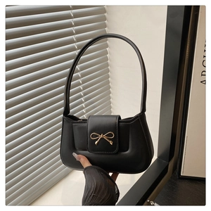 Détail d'un sac à bandoulière en cuir noir avec une boucle en métal doré en nœud
