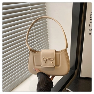 Détail du sac à main beige avec un fermoir élégant en forme de nœud doré en métal
