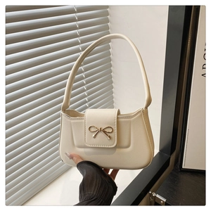 Détail d'un sac porté épaule blanc crème avec boucle nœud dorée et coutures précises