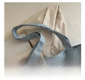 Close-up of blue canvas tote bag featuring wide handles and premium embroidered lettering