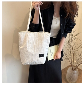 Close-up of off-white minimalist canvas tote bag with woven brand label detail