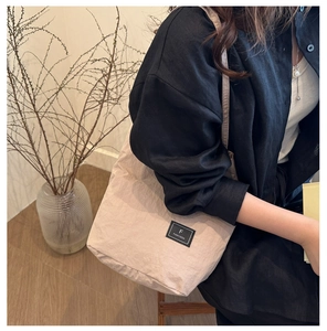Close-up of lightweight beige nylon fabric and FANYISSA brand label on the shoulder bag