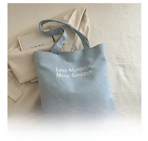 Detail of light blue canvas tote bag showing Less Mondays More Sundays slogan print