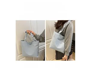 Detail view of the light blue canvas tote bag showing handheld and shoulder carry styles