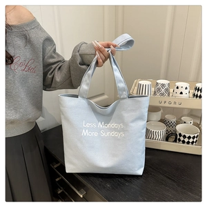 Detail of light blue canvas tote bag featuring white Less Mondays More Sundays slogan print
