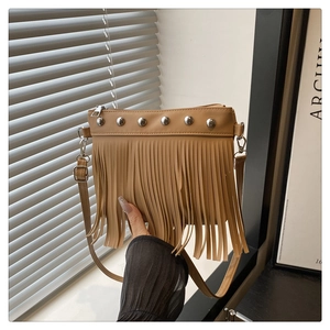 Dettaglio della borsa in pelle PU marrone con rivetti argentati e lunghe frange con tracolla