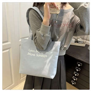 Detail of light blue canvas tote bag with 'Less Mondays More Sundays' text for daily use