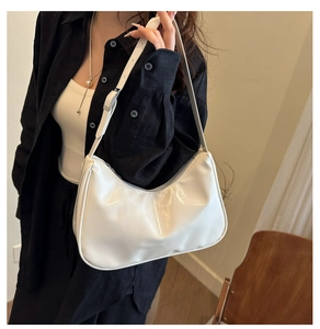 Close-up of a white minimalist half-moon shoulder bag with adjustable strap on a model