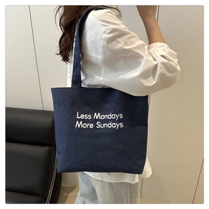 Detail of dark blue canvas tote bag with Less Mondays More Sundays white embroidery