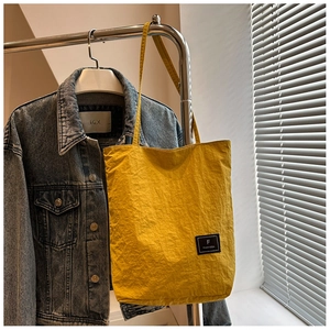 Detail of yellow canvas tote bag with textured fabric and shoulder strap on a hanger