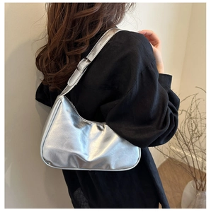 Silver metallic hobo bag with adjustable strap worn by a model in a minimalist style