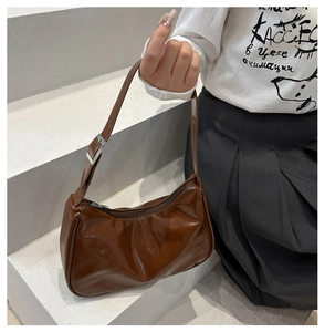 Detail view of the glossy dark brown patent leather underarm bag with silver buckle