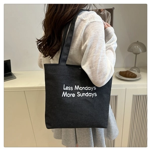 Detail of black canvas tote bag with 'Less Mondays More Sundays' embroidery for daily use