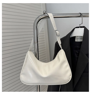 Detailed close-up of a white glossy leather hobo bag with adjustable silver buckle strap