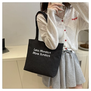Detail of black canvas tote bag featuring Less Mondays More Sundays print and long straps