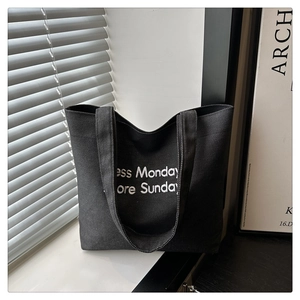 Detail of black canvas tote bag featuring white Less Monday More Sunday slogan