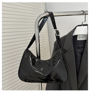 Detail of glossy black hobo bag with adjustable silver buckle on a stylish hanger