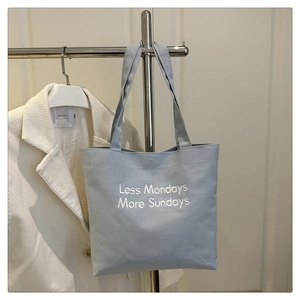 Detail of light blue canvas tote bag with Less Mondays More Sundays embroidery