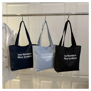 Detailed view of canvas tote bags in navy, blue and black with slogan print