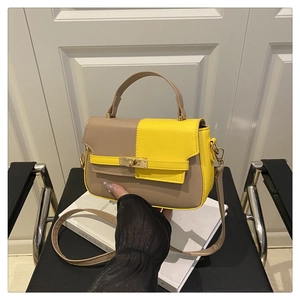 Detail of color-block saddle bag with yellow leather contrast and gold metal clasp
