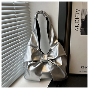 Detail der silbernen Metallic-Schultertasche mit großer Schleife und Faltenoptik