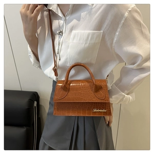 Close-up of brown crocodile pattern leather handbag with gold logo and elegant top handle