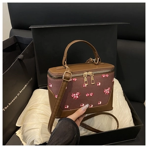 Close-up of retro cherry print handbag inside a gift box with silk lining and gold hardware