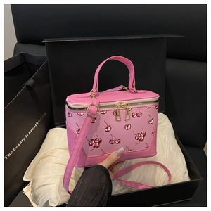 Pink crossbody bag with cherry prints displayed in a luxury gift box with silk lining