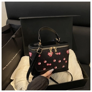 Detail of luxury black mini handbag with red cherry prints in elegant gift box
