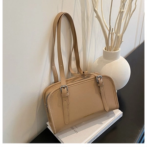 Detail of a chic beige leather crossbody bag with buckle straps and gold fashion logo