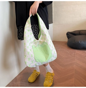 Detail of floral tote bag with green bow print, checkered pocket and drawstring tie strap