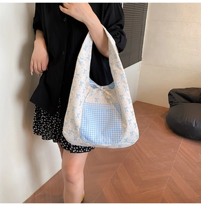Close-up of floral tote bag with blue bow pattern, lace pocket, and checkered detail