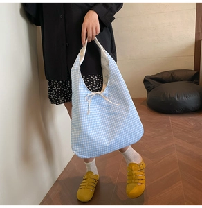 Close-up of blue gingham tote bag with floral lining and decorative bow detail